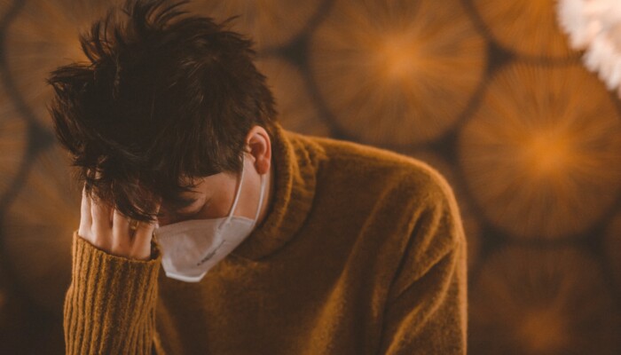 man in brown coat wearing white face mask