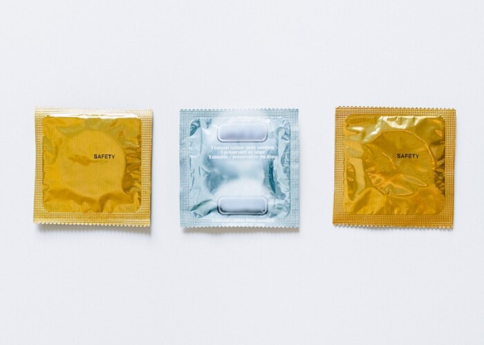 Three Condoms on White Surface