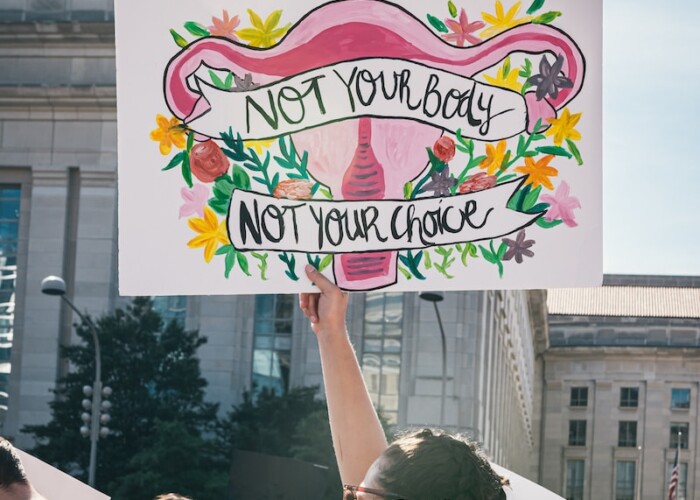 a woman holding a sign that says not your baby, not your choice